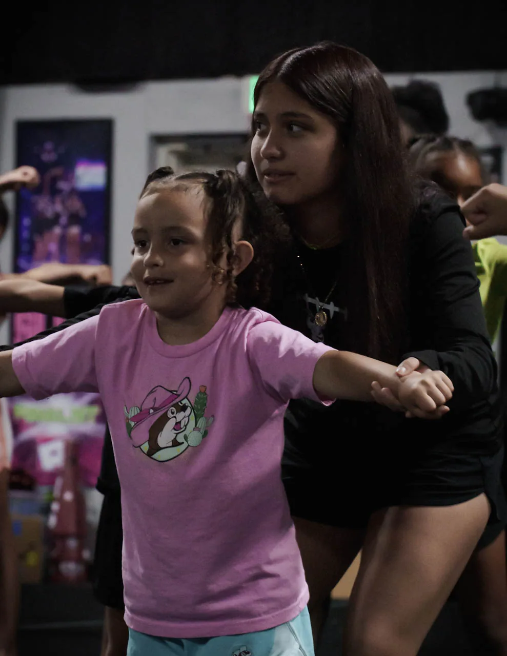 An older Category 5 athlete supporting a younger athlete through a practice motion