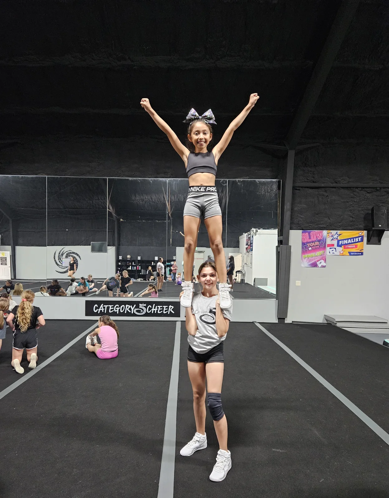 A young Category 5 flyer holding a strong extension inside the gym